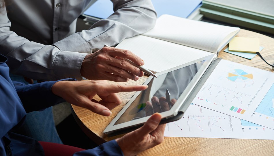 Two professionals reviewing charts and a tablet with data visualizations during an application modernization planning session
