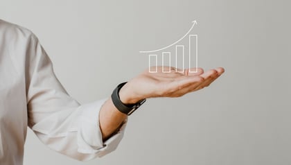 Businessman holding out an open palm with a rising bar graph illustration above it, representing the growth benefits of application modernization