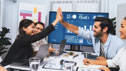 Benefits of MVP development celebrated by a team high-fiving in front of a performance dashboard.