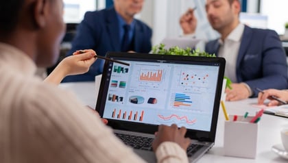 Custom ERP software development shown by a team in a meeting reviewing business dashboards on a laptop.
