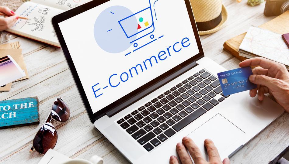 Custom ecommerce development shown by a person holding a credit card at a laptop displaying an e-commerce cart.