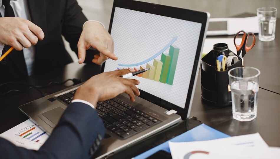 Product market fit growth chart displayed on a laptop screen as two professionals point at it.