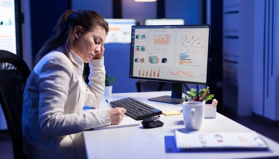 SaaS development costs reviewed by a woman at a desk with data charts on her computer screen.