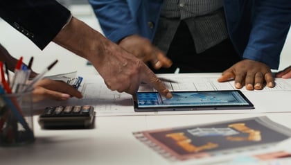 Team reviewing CAD blueprints and a tablet with technical drawings, discussing application modernization strategy