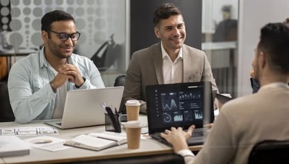 Top 10 AI consulting companies concept shown by consultants meeting around a table with analytics dashboards.