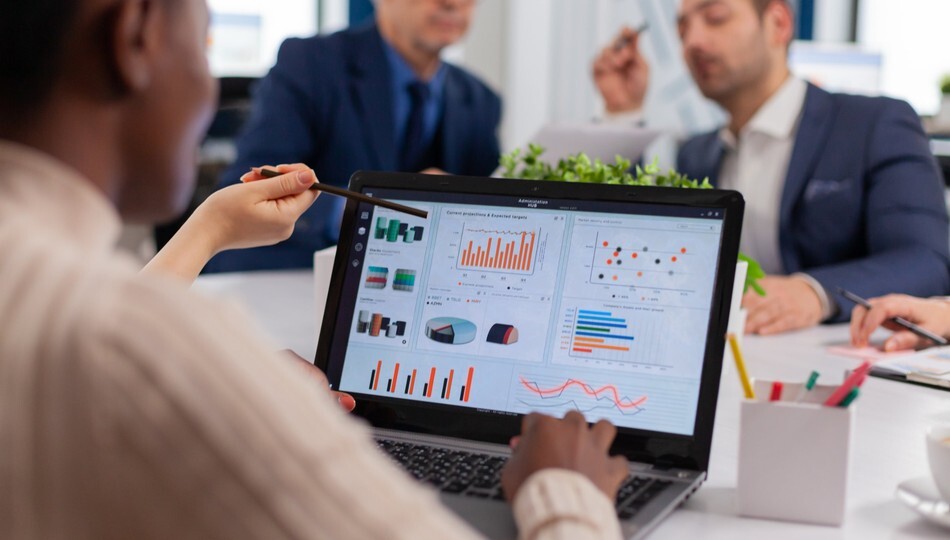 Custom ERP software development shown by a team in a meeting reviewing business dashboards on a laptop.