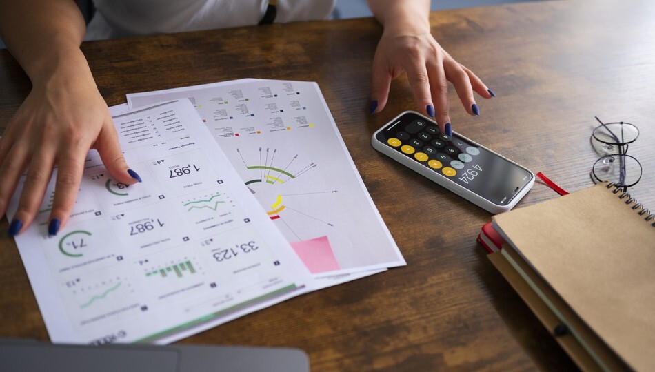 Fixed price vs time and materials comparison shown through hands reviewing financial charts and calculator.
