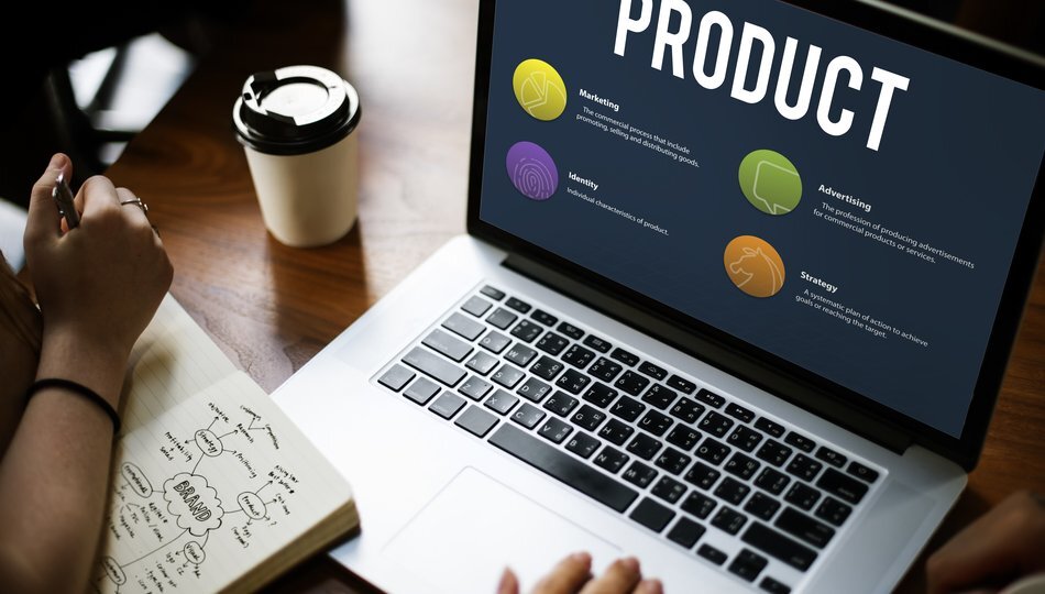 Laptop screen showing product marketing concepts beside a hand-drawn brand strategy mind map.